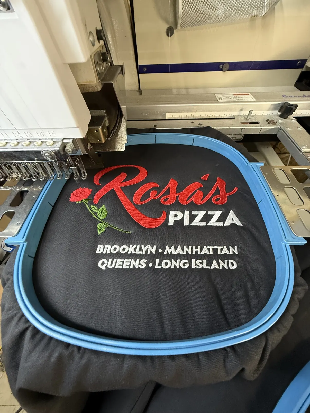 Oversized Rosa's Pizza embroidery across a garment back, in the hoop